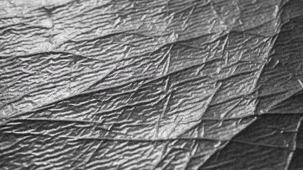 Wall Mural - Silver crumpled surface of shabby wrapping material with wrinkles and folds. Abstract shiny black and white background