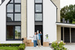 © LIGHTFIELD STUDIOS - smiling mature man and woman waving near new house