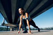 © GVS - Runner woman ready to run in running start pose on the city industrial background
