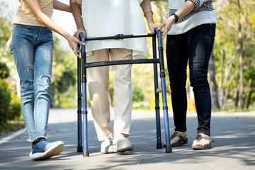 Asian senior woman use walking aid during rehabilitation after physical therapy or knee surgery, elderly people practice walking,exercising with walker for safety, family help,care,support her mother