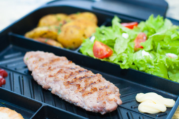 Grilled steak or cutlet, salad with tomato and green vegetables, toast, potato plan, light background, copy space. Concept healthy eating, diet, menu, nutritious food.