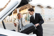 © Drobot Dean - Image of young businesslike man and woman putting luggage in car trunk