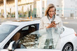© Drobot Dean - Image of businesslike woman standing by car and using cellphone outdoors