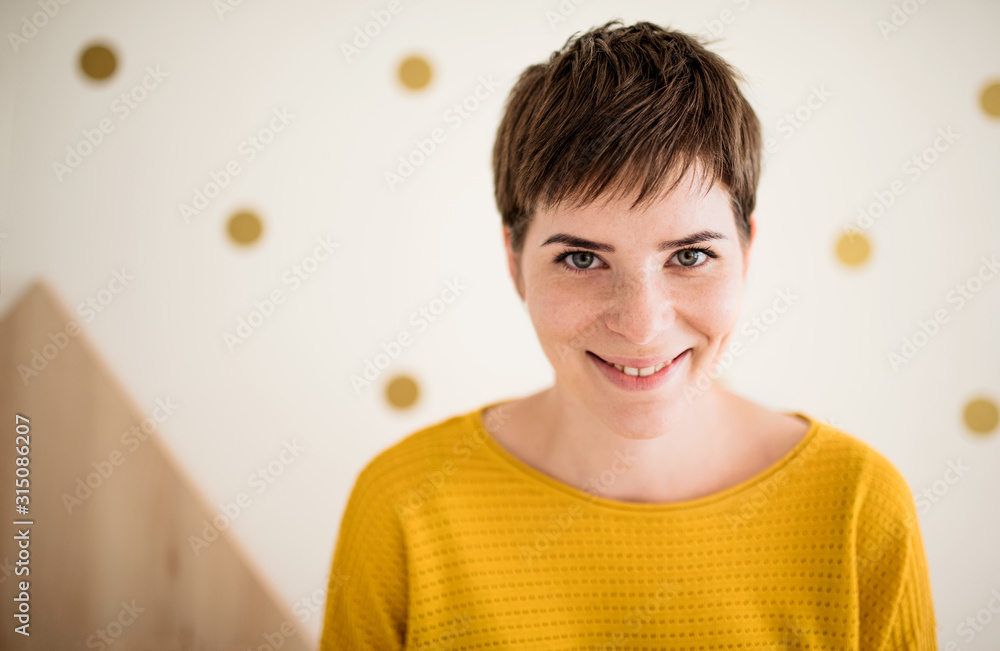 Front view of young woman standing indoors at home, close-up. - obrazy, fototapety, plakaty 