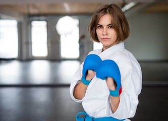 A young woman practising karate indoors in gym.