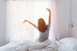 © Kittiphan - Young asian woman sitting on the bed and stretch oneself in the morning