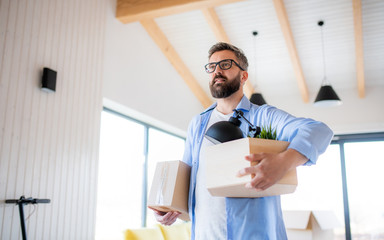 Wall Mural - Mature man with boxes moving in new unfurnished house, walking.