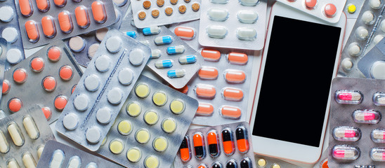 Smartphone with a dark screen. Background of colored pills. The concept of online drugstores. Copy space.