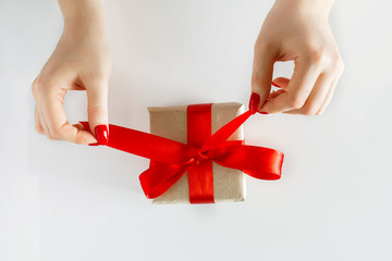 Gift with a red ribbon in hands on a white background