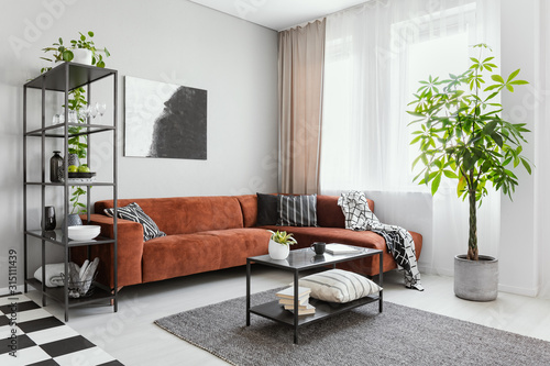 Trendy living room interior with brown corner sofa with black and white pillows and industrial coffee table