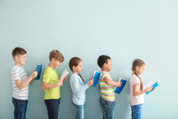 Cute little children reading books on color background