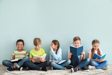 Wall Mural - Cute little children reading books on color background