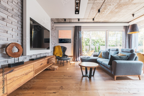 Cuadros en Lienzo Elegant living room with light wooden floor, grey couch and wing back chair and