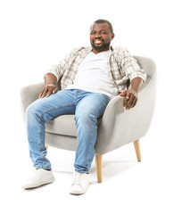 Poster - African-American man relaxing in armchair against white background