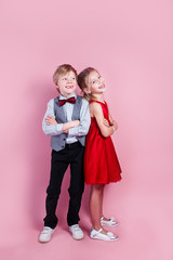 Wall Mural - Cute smiling boy and girl standing on a pink background . Valentine's Day.