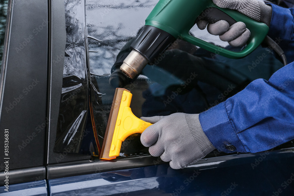 Male worker tinting car window