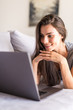 © dianagrytsku - Young woman using a laptop while relaxing on the couch