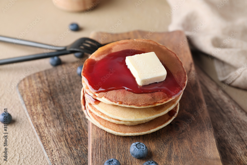 Board with stack of tasty pancakes on table