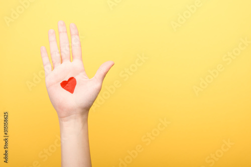 Fotografía cropped view of woman with painted heart isolated on yellow