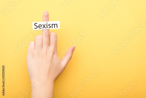 Fotomural cropped view of man showing middle finger with card sexism isolated on yellow