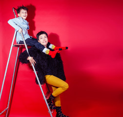 pretty young mother with little son on ladder on red background posing cheerful happy smiling, lifestyle people concept