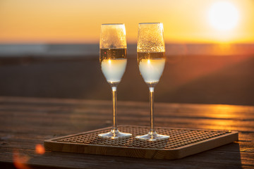 two glasses of champagne on the table at sunset