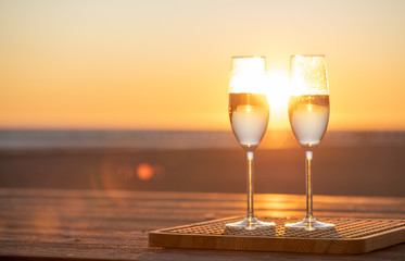 two glasses of champagne on the table at sunset