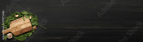 Fotografía Fresh green spinach and cutting board on dark wooden background with space for t