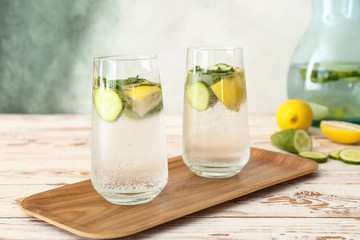 Glasses of cold cucumber water on white table