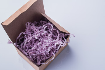 Wall Mural - Purple curvy shredded paper in a cardboard box. White isolated background.