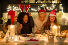 Laughing Friends Enjoying Candlelight Christmas Dinner