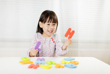Toddler Girl Learning Alphabet Letter At Home Against White Background