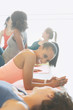 © Justin Pumfrey/Caia Image - Smiling women talking on yoga mats in exercise class gym studio