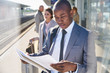 © Chris Ryan/Caia Image - Businessman reading paperwork on sunny train station platform