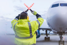 Air Traffic Controller Guiding Airplane With Wand Lights On Tarmac