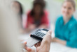© Martin Baurraud/Caia Image - Close up waitress using credit card reader at cafe table