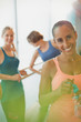 © Justin Pumfrey/Caia Image - Portrait smiling woman drinking water in exercise class gym studio