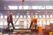 © Rafal Rodzoch/Caia Image - Steel workers fastening crane chain in factory