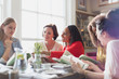 © Justin Pumfrey/Caia Image - Women friends discussing book club book at restaurant table