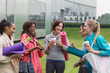 © Martin Baurraud/Caia Image - Women friends with yoga mats and coffee talking outside gym