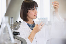 Female College Student Conducting Scientific Experiment Examining Vials In Science Laboratory Classroom