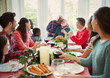 © Robert Daly/Caia Image - Affectionate multi-ethnic senior couple hugging at family Christmas dinner table