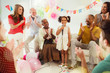 © Robert Daly/Caia Image - Multi-ethnic family clapping for girl singing karaoke microphone at birthday party