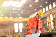 © Rafal Rodzoch/Caia Image - Engineer reviewing blueprints in steel factory