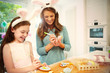 © Robert Daly/Caia Image - Mother daughter wearing costume rabbit ears coloring Easter eggs cookies