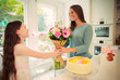 © Robert Daly/Caia Image - Affectionate daughter giving flower bouquet to mother on Mother‚Äôs Day