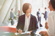 © Tom Merton/Caia Image - Smiling businesswomen meeting reviewing paperwork in office lobby