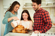 © Robert Daly/Caia Image - Family preparing Christmas dinner turkey in kitchen