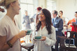 © Paul Bradbury/Caia Image - Smiling businesswomen drinking coffee networking at business conference