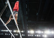 © Chris Ryan/Caia Image - Male gymnast performing upside-down handston parallel bars in arena